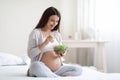 Smiling young pregnant woman eating healthy salad at home Royalty Free Stock Photo