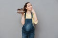 Smiling young pregnant woman holding plate with chocolate cake Royalty Free Stock Photo