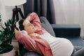 Smiling young pregnant woman leaning on couch wearing headphones closed her eyes listening music enjoy favourite song audio track Royalty Free Stock Photo