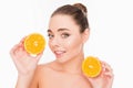 Smiling young pretty woman holding two halves of orange