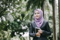 smiling young professional muslimah businesswoman holding a tablet in the park