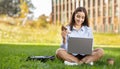 Smiling young professional woman multitasking with a laptop on her lap, enjoying a sandwich Royalty Free Stock Photo