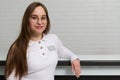 Smiling young receptionist standing at the reception desk in modern medical clinic, dentistry office or beauty spa salon