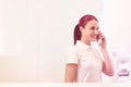 Smiling young receptionist talking on phone at checkout counter Royalty Free Stock Photo
