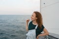 Smiling young red-haired woman on a yacht looking away in the middle of the sea Royalty Free Stock Photo