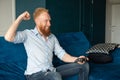 Smiling young redhead man win in video game and feel happy