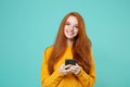 Smiling young redhead woman girl in yellow sweater posing isolated on blue turquoise background studio portrait. People Royalty Free Stock Photo