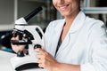 Smiling young scientist in white coat working with microscope in lab Royalty Free Stock Photo