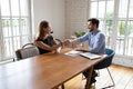 Smiling young skilled female job seeker shaking hands with hr manager. Royalty Free Stock Photo