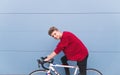 Smiling young student sitting on a white sixth bike on a background of a blue wall and looking at the camera Royalty Free Stock Photo
