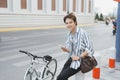 Smiling young stylish man dressed in shirt sitting with a bicycle Royalty Free Stock Photo