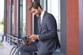 Smiling young stylish man using mobile phone while drinking coffee outdoors with bicycle. Royalty Free Stock Photo