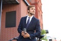 Smiling young stylish man using mobile phone while drinking coffee outdoors with bicycle. Royalty Free Stock Photo