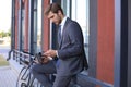 Smiling young stylish man using mobile phone while drinking coffee outdoors with bicycle. Royalty Free Stock Photo