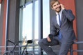 Smiling young stylish man using mobile phone while drinking coffee outdoors with bicycle. Royalty Free Stock Photo