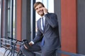 Smiling young stylish man using mobile phone while drinking coffee outdoors with bicycle. Royalty Free Stock Photo