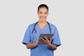 Smiling, young, tech-savvy nurse in blue scrubs using a digital tablet, symbolizing modern healthcare Royalty Free Stock Photo