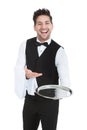 Smiling young waiter holding empty serving tray Royalty Free Stock Photo