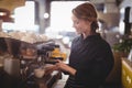 Smiling young waitress using espresso maker