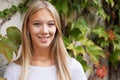 Smiling young woman against ivy-clad wall