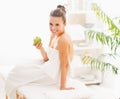 Smiling young woman with apple sitting on massage table Royalty Free Stock Photo