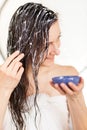 Smiling young woman applying hair mask in a bathroom