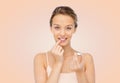 Smiling young woman applying lip balm to her lips Royalty Free Stock Photo