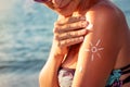 Smiling young woman applying sun block cream on beach Royalty Free Stock Photo