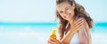 Smiling young woman applying sun block creme on beach Royalty Free Stock Photo