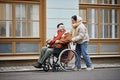 Smiling young woman assisting man in wheelchair in date together in city streets Royalty Free Stock Photo