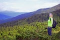 Smiling young woman with backpack standing on mountin peak