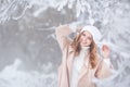 Smiling young woman in a beige and white dress in a winter forest