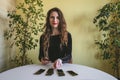 Smiling young woman in a black velvet dress lays out cards on the table Royalty Free Stock Photo