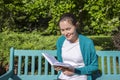 Smiling young woman with a book in the park. Photo of a college student reading a book Royalty Free Stock Photo