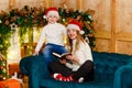 Smiling young woman and boy sitting on sofa with book near Christmas fireplace Royalty Free Stock Photo