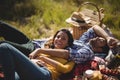 Smiling young woman with boyfriend relaxing on picnic blanket at olive farm