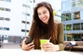 Smiling young woman with cellphone and coffee