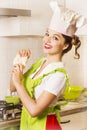 Smiling young woman in chef hat cooking dough