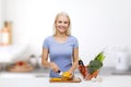 Smiling young woman chopping vegetables on kitchen Royalty Free Stock Photo