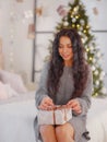 Smiling young woman with christmas present box near christmas tree Royalty Free Stock Photo