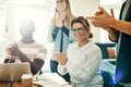 Smiling young woman clapping with colleagues in a modern office Royalty Free Stock Photo