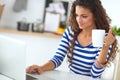 Smiling young woman with coffee cup and laptop in