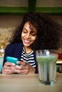 Smiling young woman in coffee shop using mobile phone Royalty Free Stock Photo