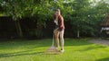 Smiling young woman collecting fallen leaves with garden rake from grass lawn. Concept of houseworking, gardening and