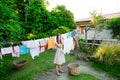 Smiling young woman in colorful dress hanging laundry on clothesline at the backyard Royalty Free Stock Photo