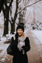 Smiling Young Woman in Cozy Clothing using mobile phone and holding coffee cup on winter day