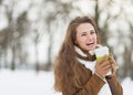 Smiling young woman with cup of hot beverage in winter park Royalty Free Stock Photo