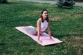 Smiling young woman doing yoga in park. Beautiful woman in sports clothes is lying in Cobra pose, doing Bhujangasana Royalty Free Stock Photo