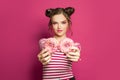 Smiling young woman with donuts on pink background