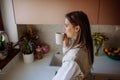 Smiling young woman with dreamy face drinking morning coffee at her kitchen. Royalty Free Stock Photo